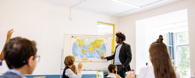 Pädagogin im Gespräch mit Kindern im Klassenzimmer – Deeskalation in der Schulkindbetreuung